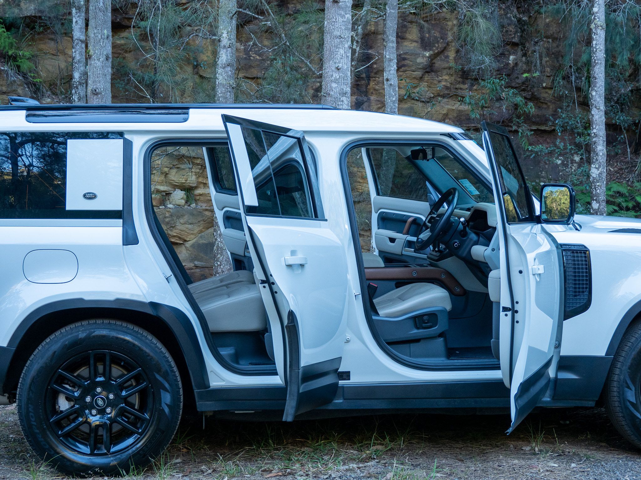 White Land Rover Defender with every door open in bushland after a full detail