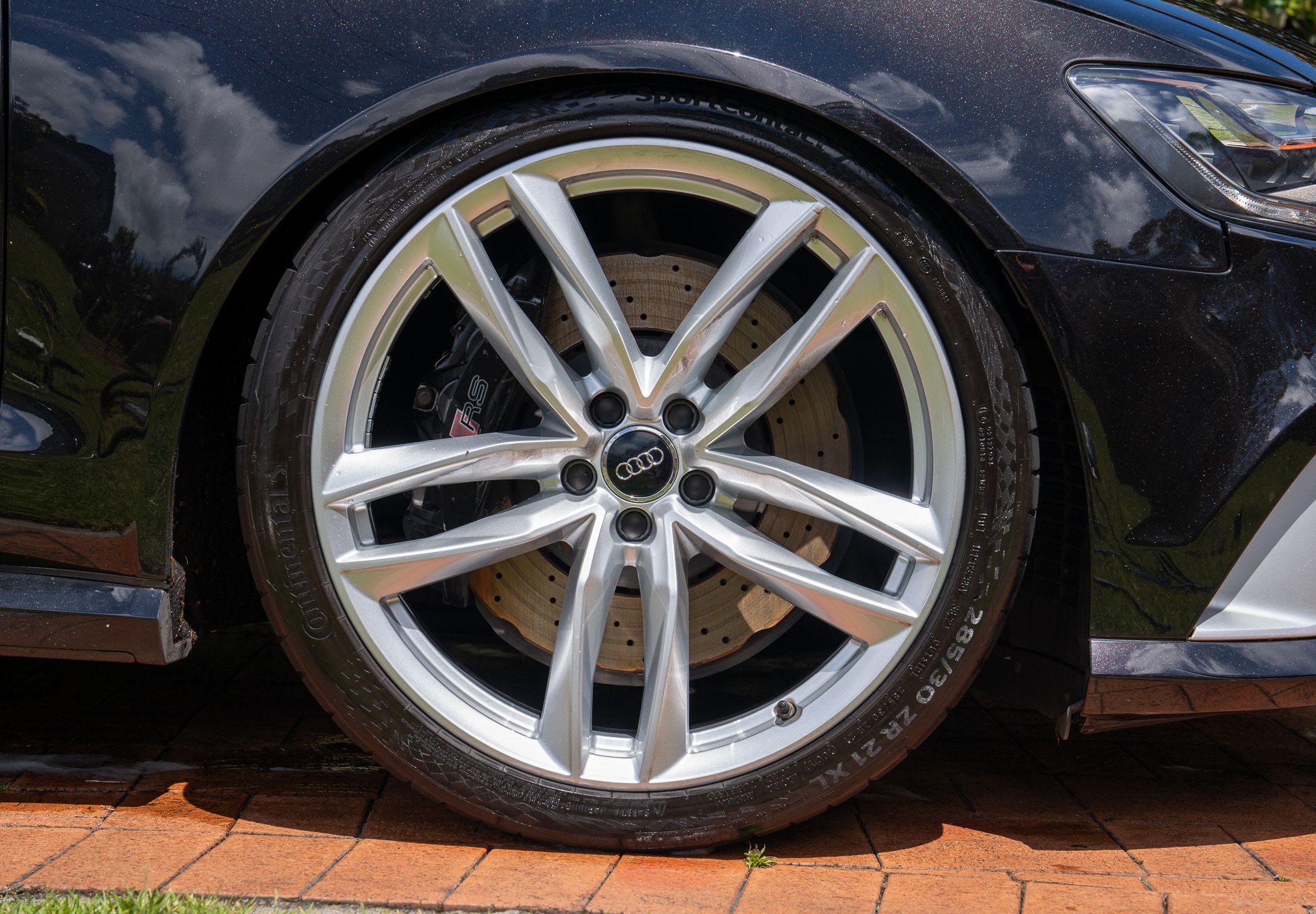Audi RS6 alloy wheel and gloss black paint reflecting the sky